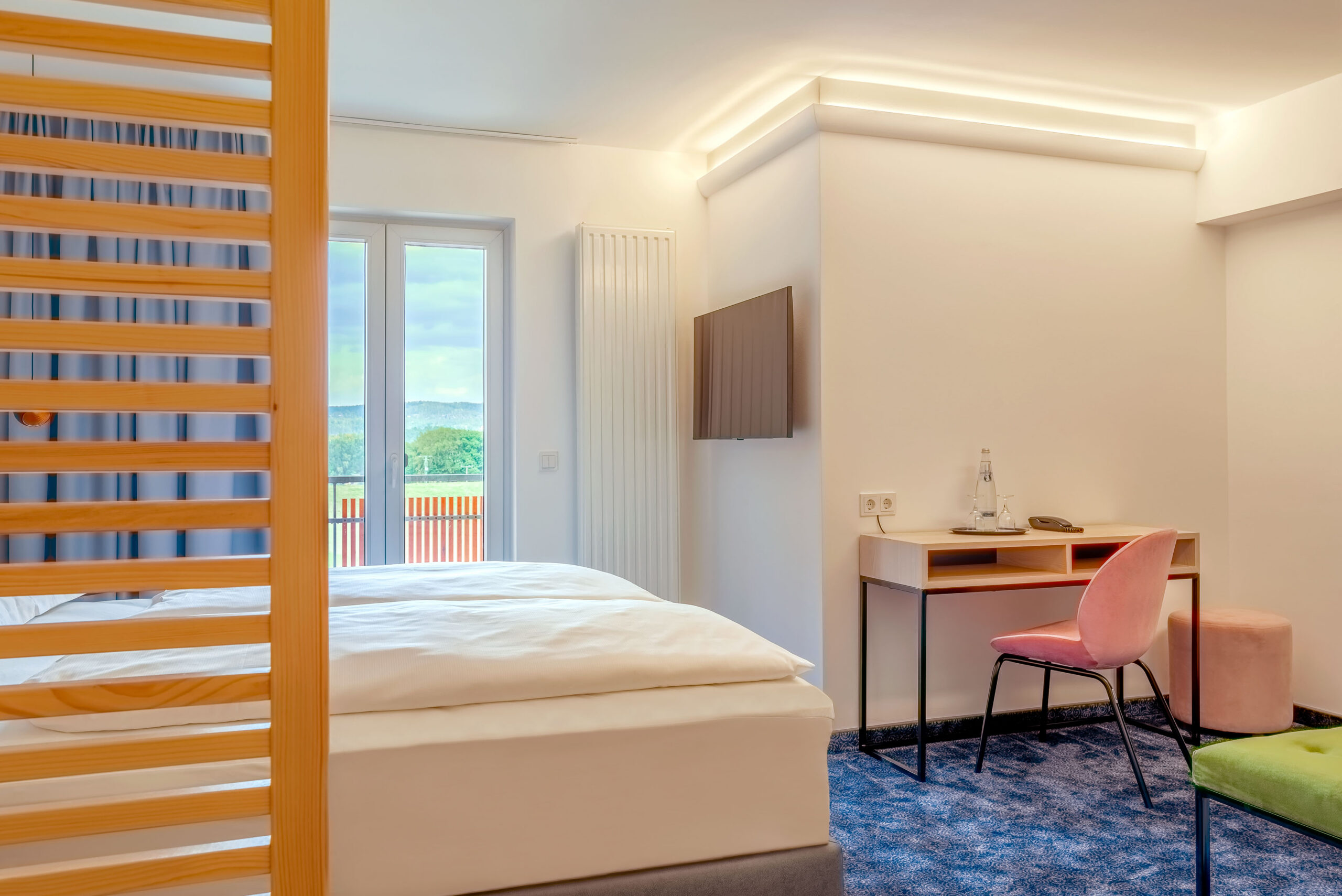 Zimmer mit Balkontür und Schreibtisch